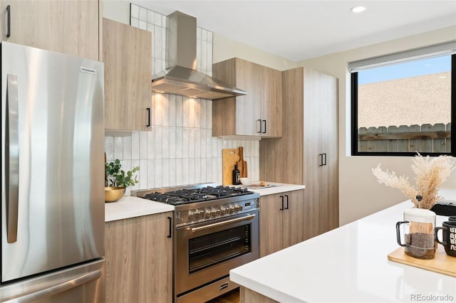 kitchen featuring wall chimney range hood, appliances with stainless steel finishes, modern cabinets, tasteful backsplash, and light countertops