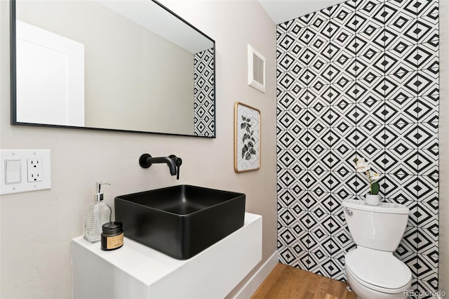 bathroom with toilet, visible vents, a sink, and wood finished floors