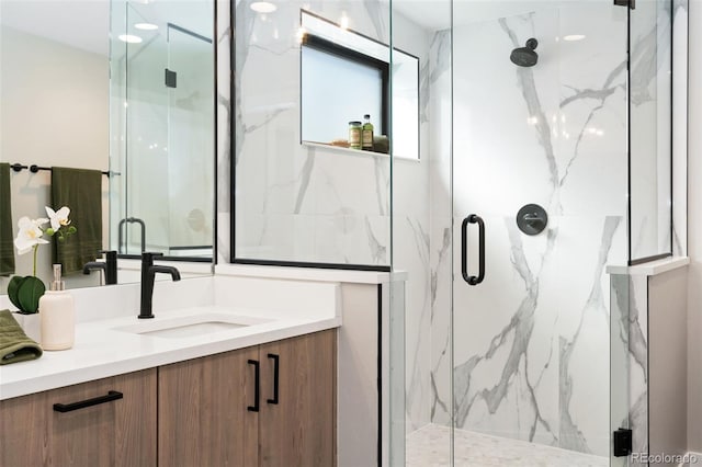 bathroom featuring vanity and a marble finish shower