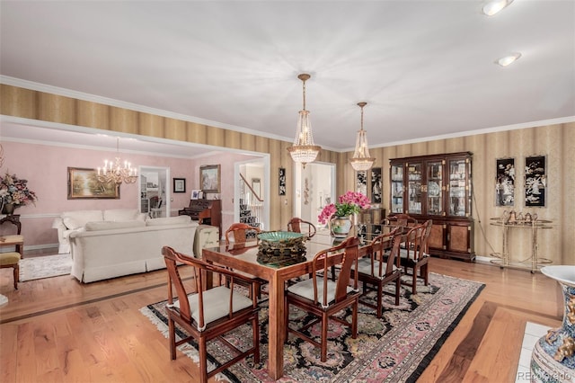 dining area with ornamental molding, light wood-type flooring, and a notable chandelier