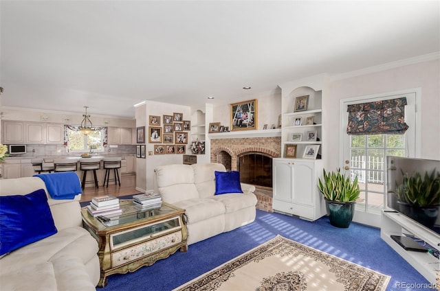 living room with built in shelves, a brick fireplace, and ornamental molding