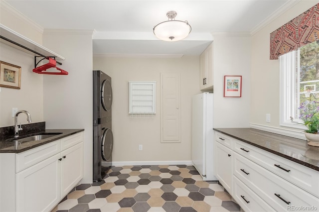 washroom featuring crown molding, sink, and stacked washer / dryer