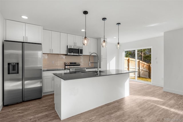 kitchen with sink, an island with sink, pendant lighting, white cabinets, and appliances with stainless steel finishes