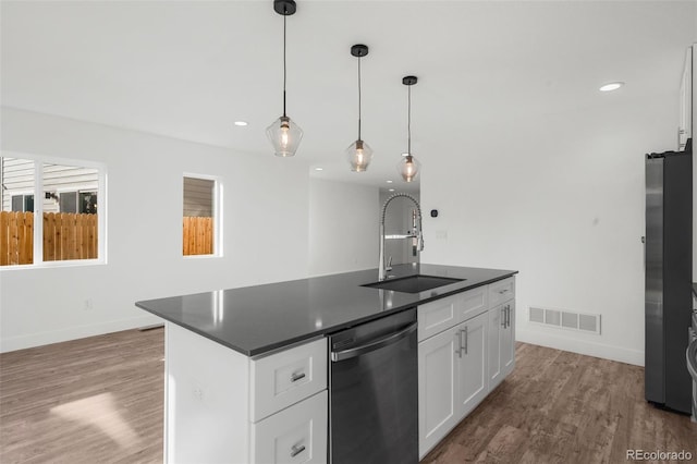 kitchen with appliances with stainless steel finishes, sink, decorative light fixtures, white cabinets, and an island with sink