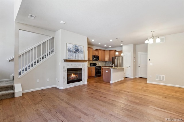 16062 W 62nd Ln, Arvada, CO 80403 - unfurnished living room featuring light wood-style floors, stairway, a chandelier, recessed lighting, and a fireplace