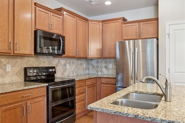 16062 W 62nd Ln, Arvada, CO 80403 - kitchen with stainless steel appliances, brown cabinetry, and tasteful backsplash