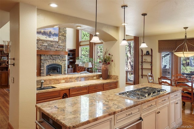 20050 Lost Arrowhead Dr, Monument, CO 80132 - kitchen with stainless steel gas cooktop, a sink, wood finished floors, light stone countertops, and pendant lighting