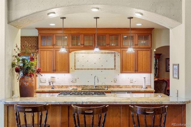 20050 Lost Arrowhead Dr, Monument, CO 80132 - kitchen with a sink, backsplash, light stone countertops, glass insert cabinets, and arched walkways