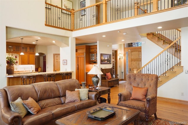20050 Lost Arrowhead Dr, Monument, CO 80132 - living room with a towering ceiling, light wood-style floors, arched walkways, stairs, and baseboards