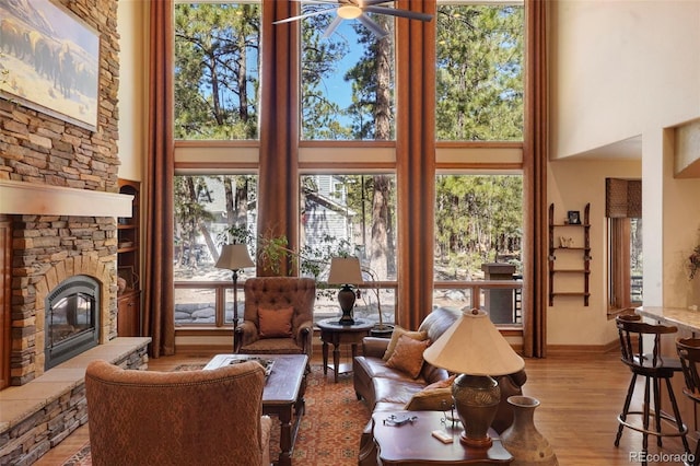 20050 Lost Arrowhead Dr, Monument, CO 80132 - living room with a high ceiling, a ceiling fan, plenty of natural light, a fireplace, and light wood-style floors