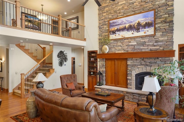 20050 Lost Arrowhead Dr, Monument, CO 80132 - living room featuring baseboards, wood finished floors, stairway, a stone fireplace, and a high ceiling