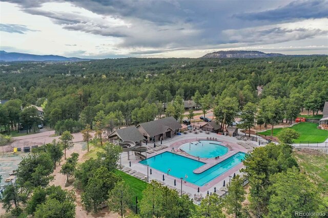 20050 Lost Arrowhead Dr, Monument, CO 80132 - drone / aerial view of a heavily wooded area, a mountain backdrop, and a pool area