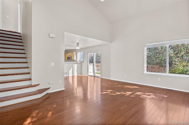 unfurnished living room featuring wood-type flooring, high vaulted ceiling, and plenty of natural light