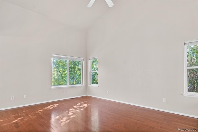 spare room with ceiling fan, high vaulted ceiling, and wood-type flooring