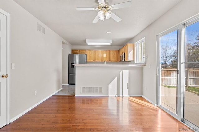 kitchen with ceiling fan, stainless steel appliances, light brown cabinets, and hardwood / wood-style floors