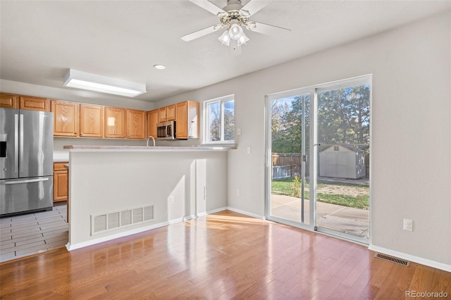 kitchen with light hardwood / wood-style floors, light brown cabinets, stainless steel appliances, and ceiling fan