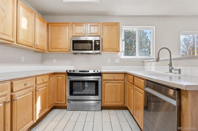 kitchen featuring stainless steel appliances, sink, and light brown cabinetry