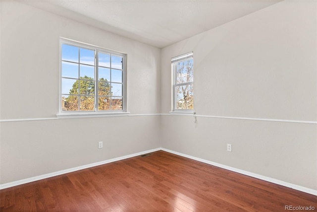 empty room with hardwood / wood-style floors and plenty of natural light