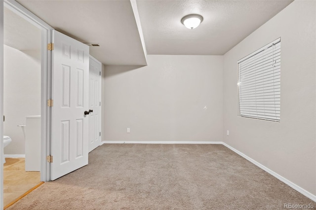 basement featuring light carpet and a textured ceiling