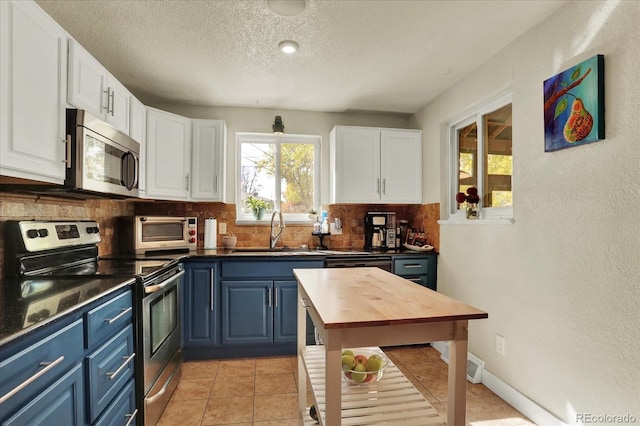 kitchen with blue cabinetry, stainless steel appliances, white cabinetry, and sink