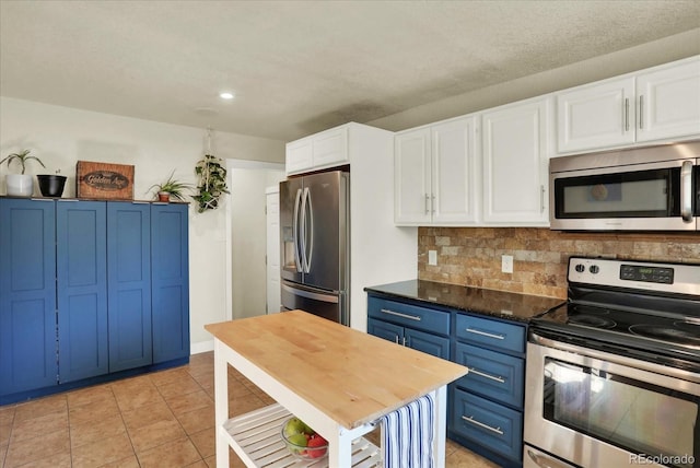 kitchen with blue cabinets, tasteful backsplash, light tile patterned flooring, white cabinetry, and stainless steel appliances