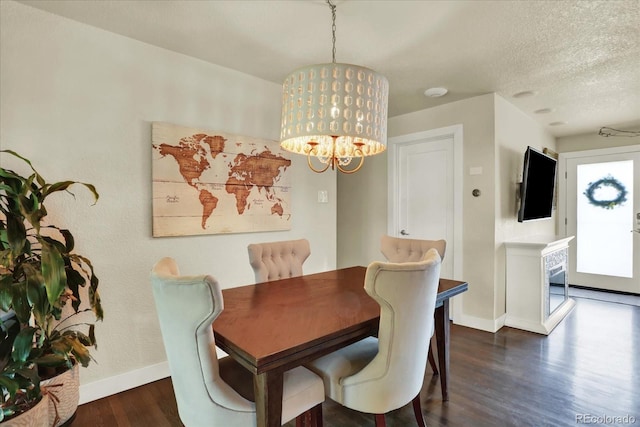 dining area with dark wood-type flooring, a textured ceiling, and an inviting chandelier