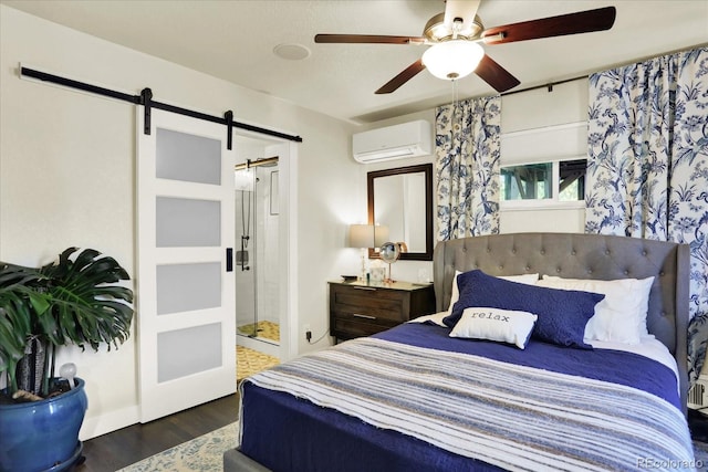 bedroom featuring ceiling fan, dark wood-type flooring, a wall mounted air conditioner, a barn door, and ensuite bathroom