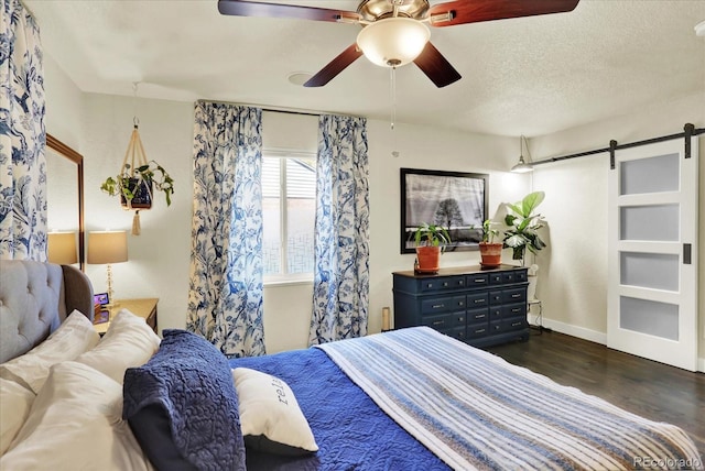 bedroom featuring a barn door, dark hardwood / wood-style floors, and ceiling fan