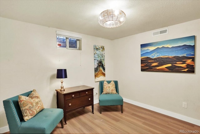 living area with a textured ceiling and light hardwood / wood-style flooring