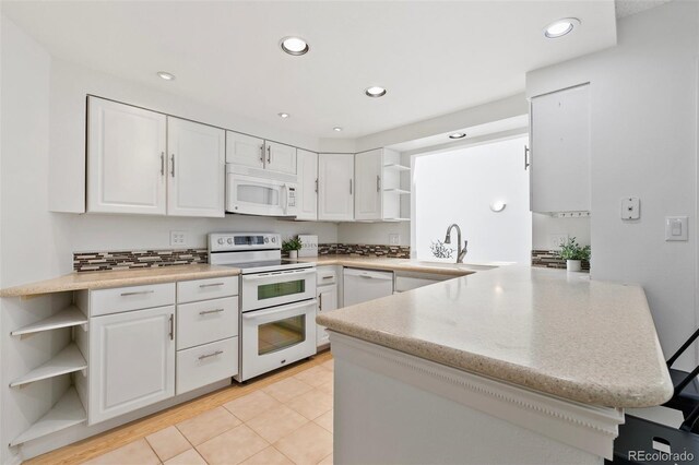 2049 Sussex Ln, Colorado Springs, CO 80909 - kitchen with white appliances, open shelves, a peninsula, white cabinets, and recessed lighting