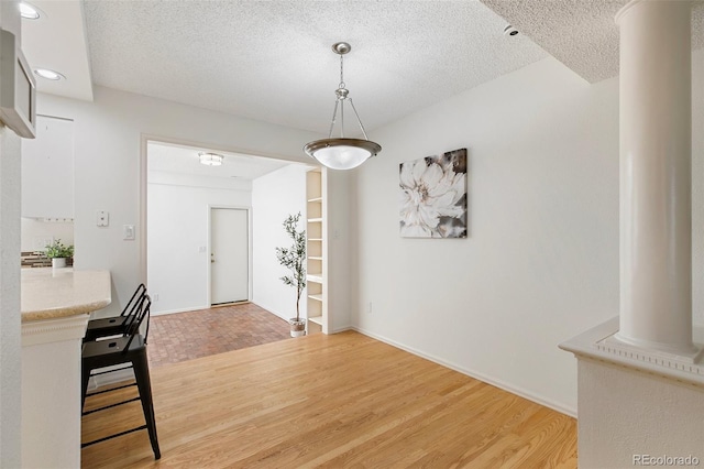 2049 Sussex Ln, Colorado Springs, CO 80909 - unfurnished dining area with ornate columns, light wood-style floors, a textured ceiling, and recessed lighting