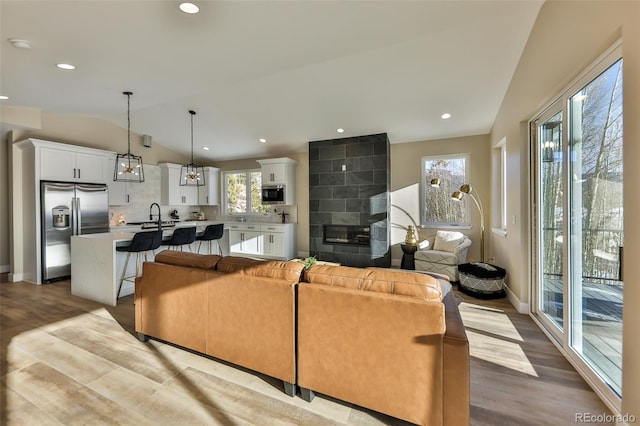 living room featuring recessed lighting, vaulted ceiling, baseboards, and wood finished floors