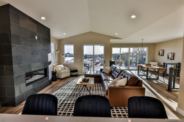 living area with baseboards, a tiled fireplace, lofted ceiling, wood finished floors, and recessed lighting