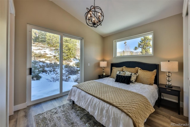 bedroom with access to outside, multiple windows, vaulted ceiling, and wood finished floors