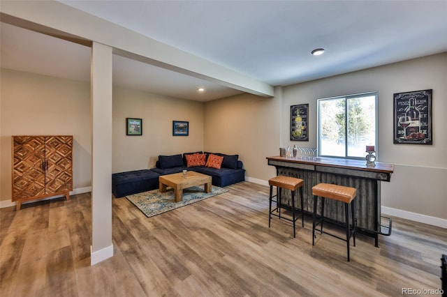 living room with indoor wet bar, beamed ceiling, baseboards, and wood finished floors