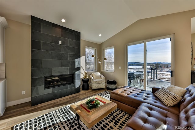 living area featuring baseboards, a tiled fireplace, wood finished floors, vaulted ceiling, and recessed lighting