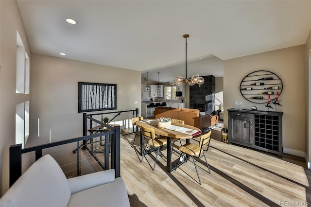 dining area with baseboards, light wood finished floors, recessed lighting, and a notable chandelier