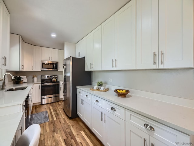 50 Yarrow St, Lakewood, CO 80226 - kitchen featuring appliances with stainless steel finishes, a sink, light countertops, white cabinetry, and light wood finished floors