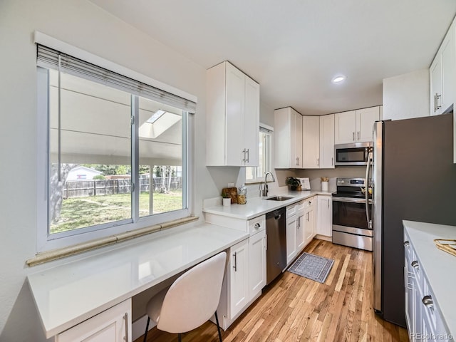 50 Yarrow St, Lakewood, CO 80226 - kitchen with stainless steel appliances, a sink, light wood-type flooring, white cabinetry, and light countertops
