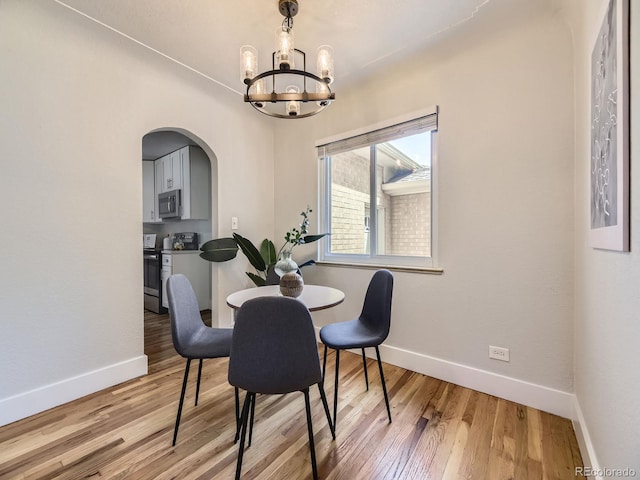 50 Yarrow St, Lakewood, CO 80226 - dining space with a chandelier, baseboards, arched walkways, and wood finished floors