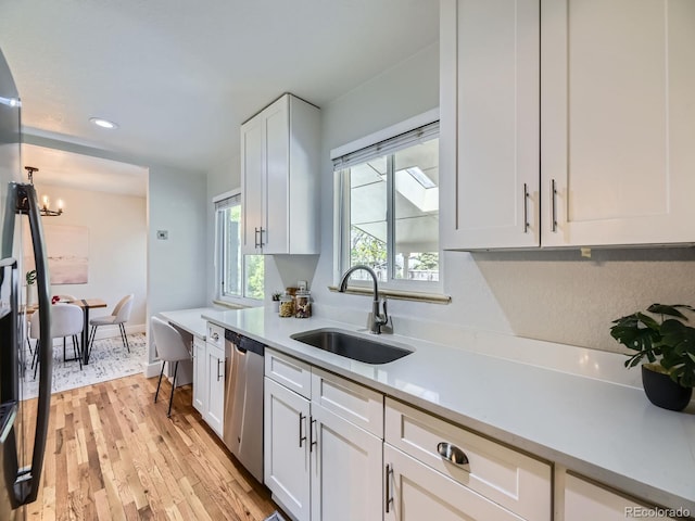 50 Yarrow St, Lakewood, CO 80226 - kitchen featuring a sink, stainless steel dishwasher, light countertops, white cabinetry, and a chandelier
