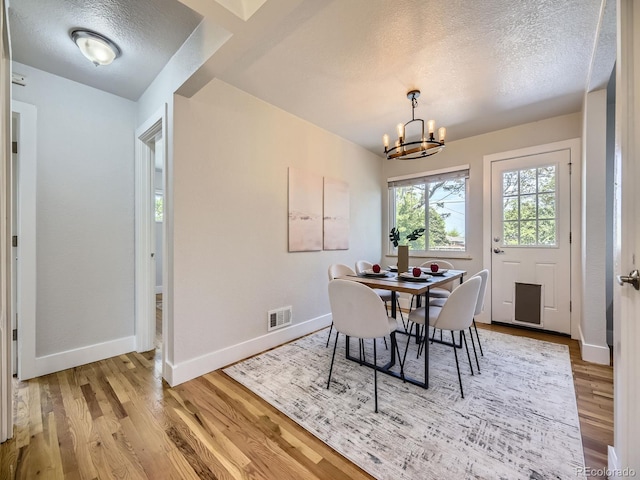 50 Yarrow St, Lakewood, CO 80226 - dining space featuring a textured ceiling, a chandelier, baseboards, and wood finished floors
