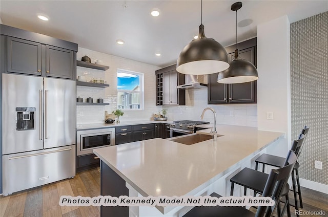 kitchen with a kitchen bar, sink, hanging light fixtures, high quality appliances, and kitchen peninsula