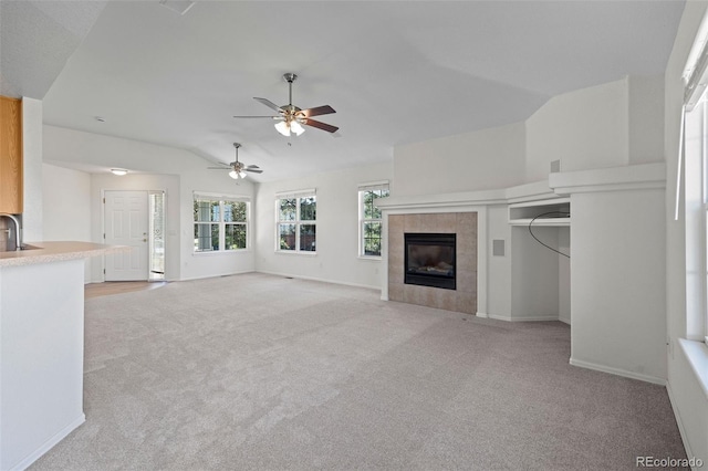 7713 S Zante Ct, Aurora, CO 80016 - unfurnished living room featuring lofted ceiling, light colored carpet, a tiled fireplace, and ceiling fan
