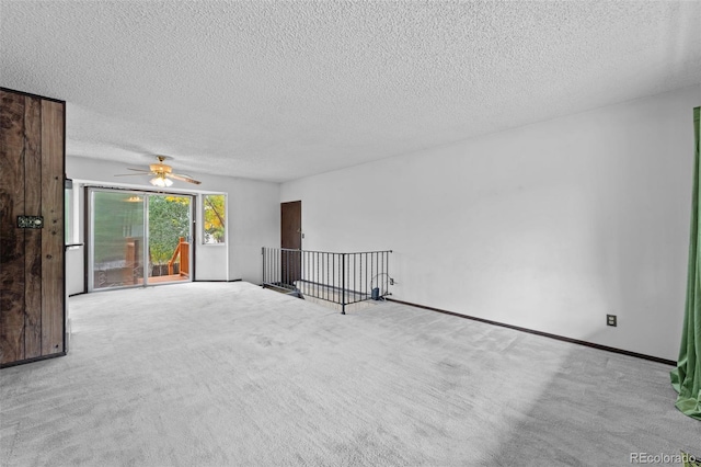 empty room with ceiling fan, light colored carpet, and a textured ceiling