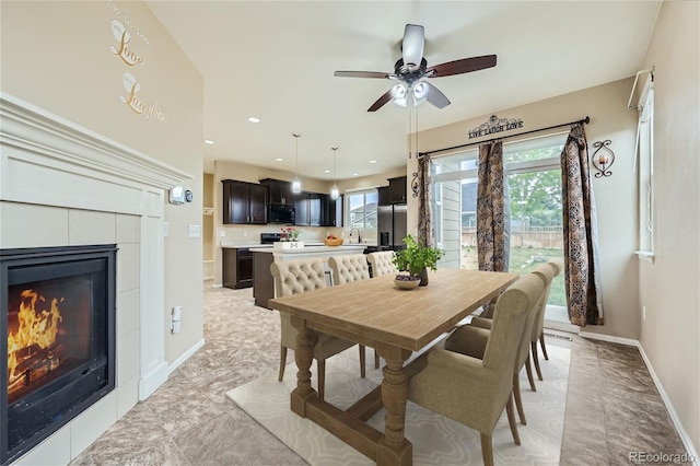 dining area with a tiled fireplace, sink, and a wealth of natural light