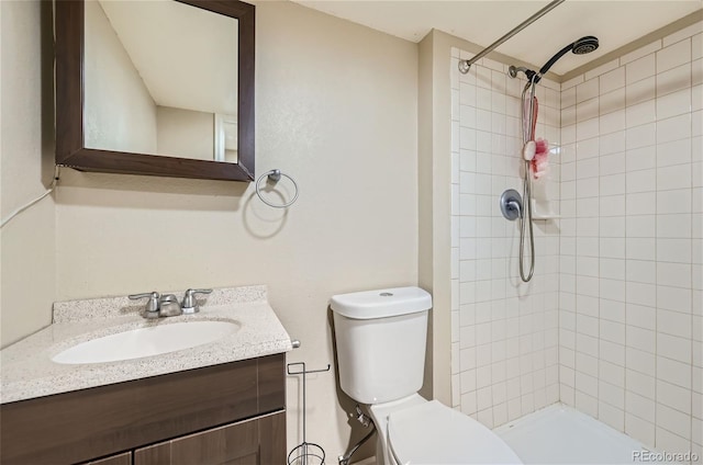 bathroom with vanity, toilet, and tiled shower