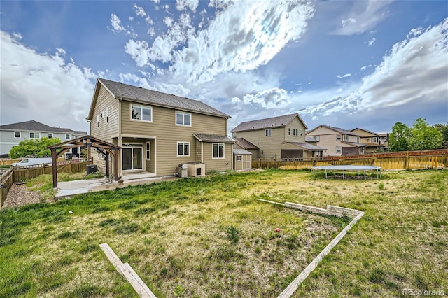 rear view of property with a gazebo, a patio area, a trampoline, and a lawn