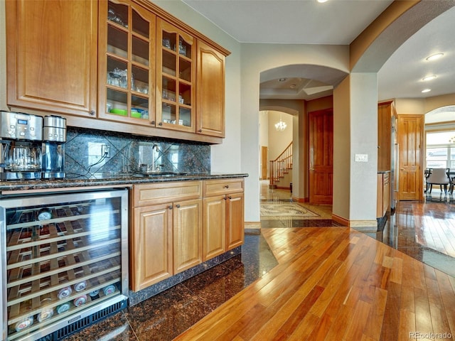 6533 S Quemoy Way, Aurora, CO 80016 - bar featuring beverage cooler, baseboards, arched walkways, and dark wood-style floors