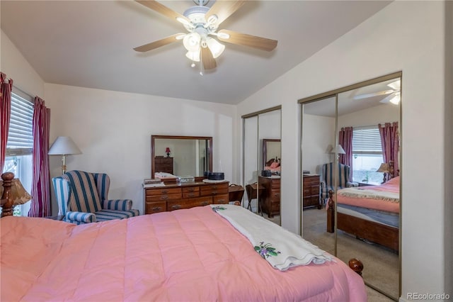 carpeted bedroom featuring lofted ceiling, a ceiling fan, and multiple closets